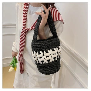 Detail of hand-woven black bucket bag featuring decorative white circular accents