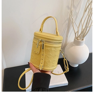 Detail view of yellow lychee leather bucket bag with bear embossing and gold rivets