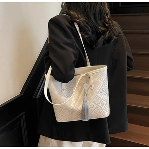 Dettaglio borsa tote in jacquard bianco crema con motivi floreali retrò e nappa grigia
