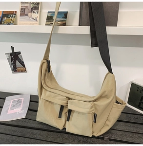 Detail of khaki nylon crossbody bag showing utility flap pockets and adjustable black strap