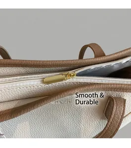 Close-up of litchi textured leather tote bag with smooth golden metal zipper detail