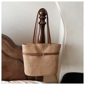 Detail of woven straw tote bag with brown leather strap and decorative metal buckle