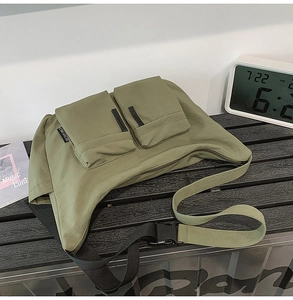 Detail of olive green canvas messenger bag featuring front pockets and buckle strap