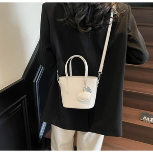 Close-up of creamy white bucket bag in lychee leather with heart charm and silver hardware