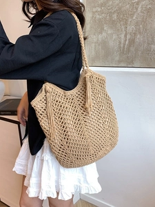 Large khaki woven tote bag with fringe details and hollow knit design shown on a model