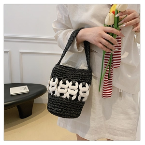 Close-up of black woven straw bucket bag with white decorative chain links for women