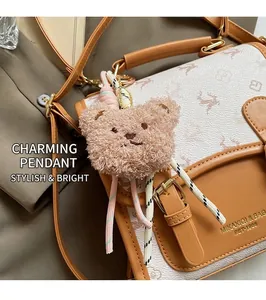 Detailed close-up of brown patchwork bag featuring a deer logo and plush bear charm