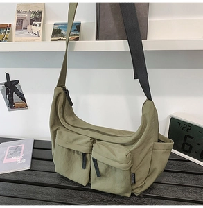 Detailed view of olive green nylon crossbody bag with dual utility pockets and black strap