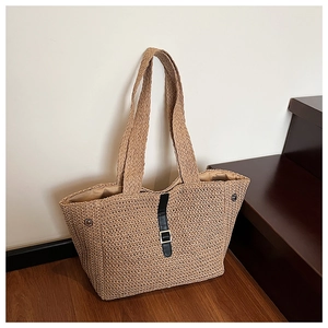 Détail d'un cabas en paille tressée avec sangle en cuir noir et boucle dorée chic