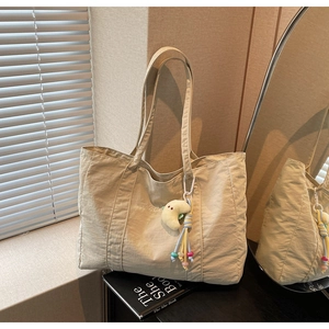Detail of beige canvas tote bag with TaoCa embroidery and moon plush charm