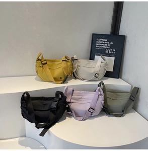 Five assorted colors of nylon crossbody bags displayed on a modern minimalist pedestal