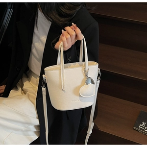 Detail of white lychee texture bucket bag with Solar Kiss logo and heart pendant charm