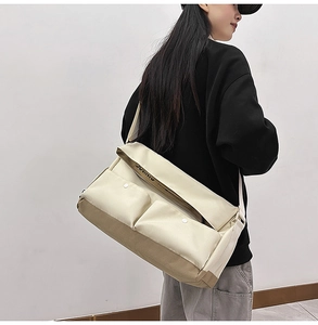 Détail du grand sac bandoulière en toile avec poches contrastées kaki et boutons pression