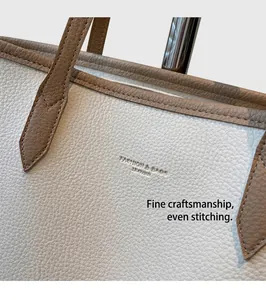 Detail view of cream pebble leather tote with brown trim and embossed fashion text