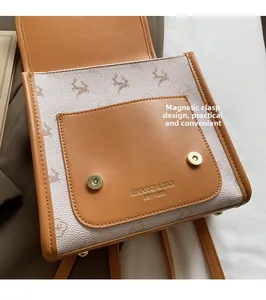 Detail of magnetic snap closures and logo on a vintage patterned brown leather backpack
