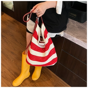 Close-up of red and white striped knit tote bag with hollow woven texture and leather handle
