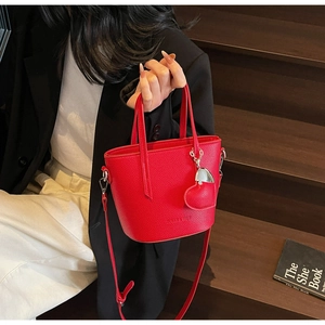 Detail of red pebbled leather bucket bag with heart charm and brand logo embossing