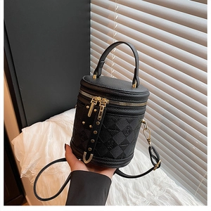 Detail of black pebbled leather bucket bag featuring quilted texture and gold hardware