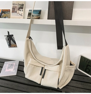 Detail view of the beige messenger bag with double front pockets and black drawstrings