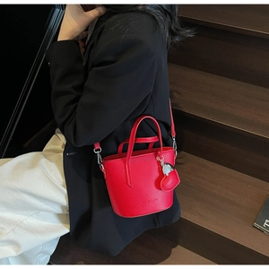 Red lychee pattern bucket bag with heart charm shown on model in stylish interior