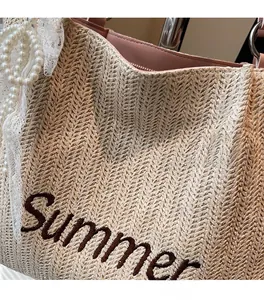 Detail of straw tote bag featuring Summer embroidery with pearl chain and lace trim