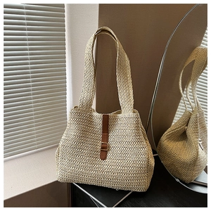 Détail de sac cabas en paille tressé à la main avec sangle en cuir brun et boucle métallique