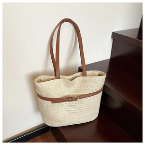 Detail of the natural woven straw texture with brown leather strap and metal buckle accent