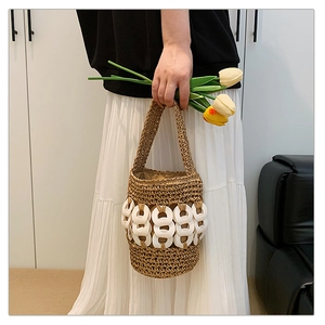 Detail of hand-woven straw bucket bag with decorative white resin rings and handle