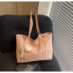 Detail of peach canvas tote bag with embroidery, moon plush charm and long strap