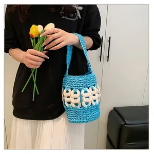 Detail of blue hand-woven straw bucket bag featuring white circular accents and handle