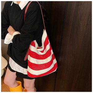 Detail of red and white striped knit tote bag showing woven texture and shoulder strap