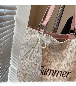 Detail of woven straw tote bag with pink leather handle and lace beaded bow ornament