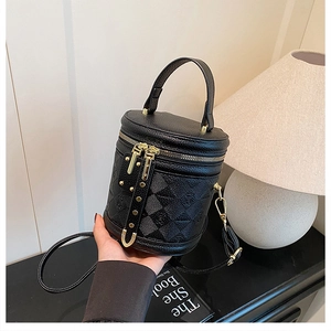 Detail of black pebbled leather bucket bag with embossed checkers and gold zippers