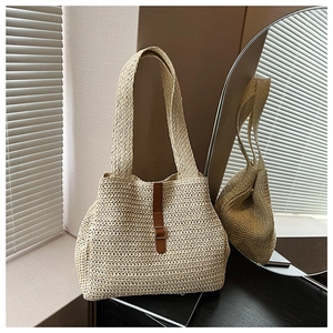 Gros plan d'un sac cabas en paille tressée avec lanière en cuir brun et boucle en métal