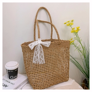 Dettaglio borsa tote in paglia intrecciata con design a rete e fiocco in pizzo bianco
