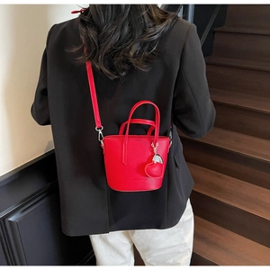 Detailed view of red bucket bag with heart charm and lychee grain leather texture