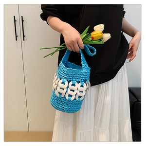 Close-up of bright blue hand-woven crochet bucket bag with white ring buckle details