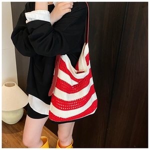 Close-up of red and white striped knitted tote bag with hollow out texture and leather strap