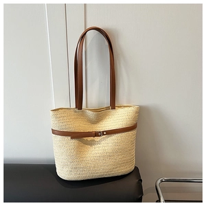 Detailed texture of woven straw tote bag with brown leather straps and metal buckle