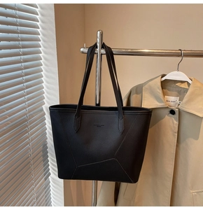 Detail of black tote bag showing premium pebble grain texture and geometric stitching