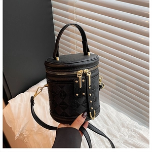 Detail of black leather bucket bag with quilted texture and golden metal zippers