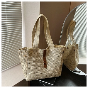 Détail d'un sac cabas en paille beige avec sangle en cuir marron et boucle métallique