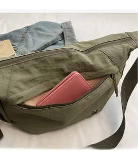 Detail showing high-capacity army green nylon crossbody bag with a pink leather wallet