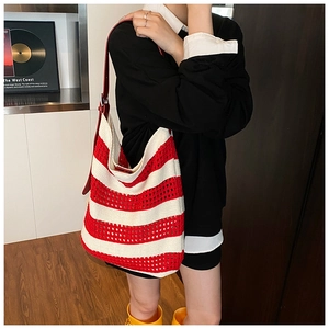 Detail of red and white striped knit tote bag showing hollow crochet texture and leather strap