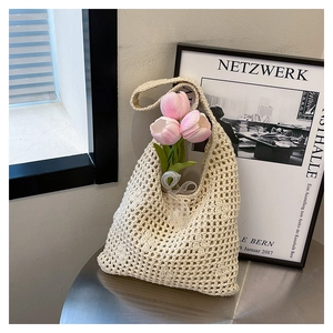 Detail of hollow out crochet bucket bag in cream white on a minimalist steel table