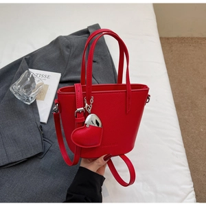 Detail of red lychee textured bucket bag with heart pendant and SOLAR & MISS logo