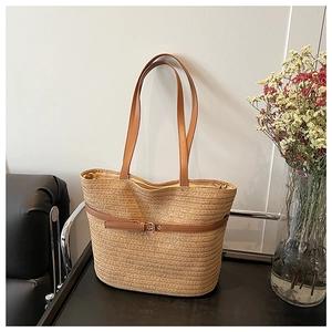 Detail of woven straw tote bag with brown leather straps and metal buckle decoration