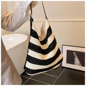 Detail of hand-woven striped tote bag with black and white texture and leather strap