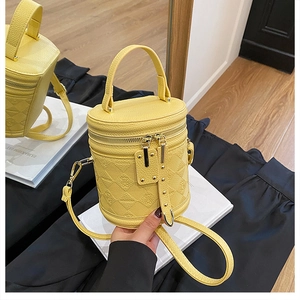 Detail of yellow lychee pattern leather bucket bag with quilted bear design and dual zippers