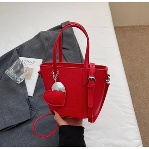 Detail of red bucket bag showing litchi texture leather and heart-shaped pendant charm